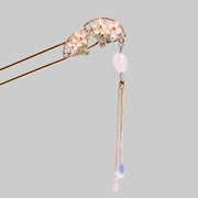 Decorative hairpin with gemstones and a tassel on a pink background
